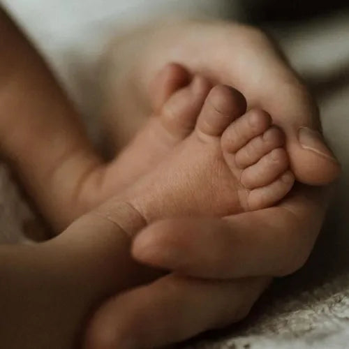Baby feet held by mom