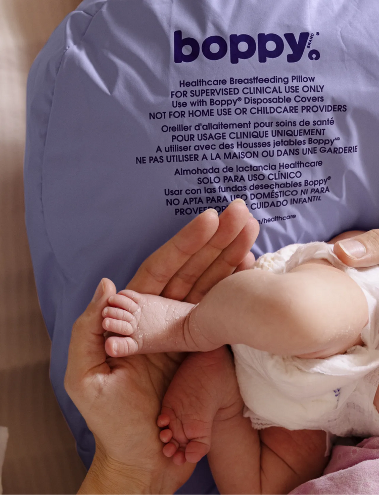 Boppy Healthcare Nursing Pillow with a newborn lounging on it